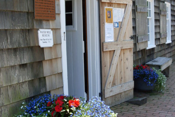 Historic wooden building entrance with colorful flower pots.