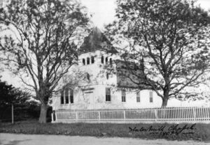 Historic church surrounded by trees and fence.