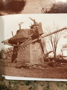 Old windmill with broken blades and trees.
